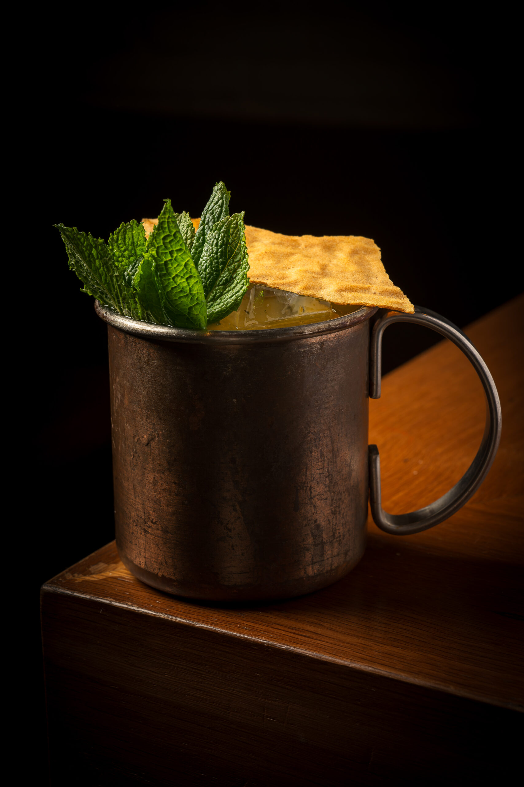 Mule de altura en taza de cobre con menta y una teja crujiente, sobre la barra