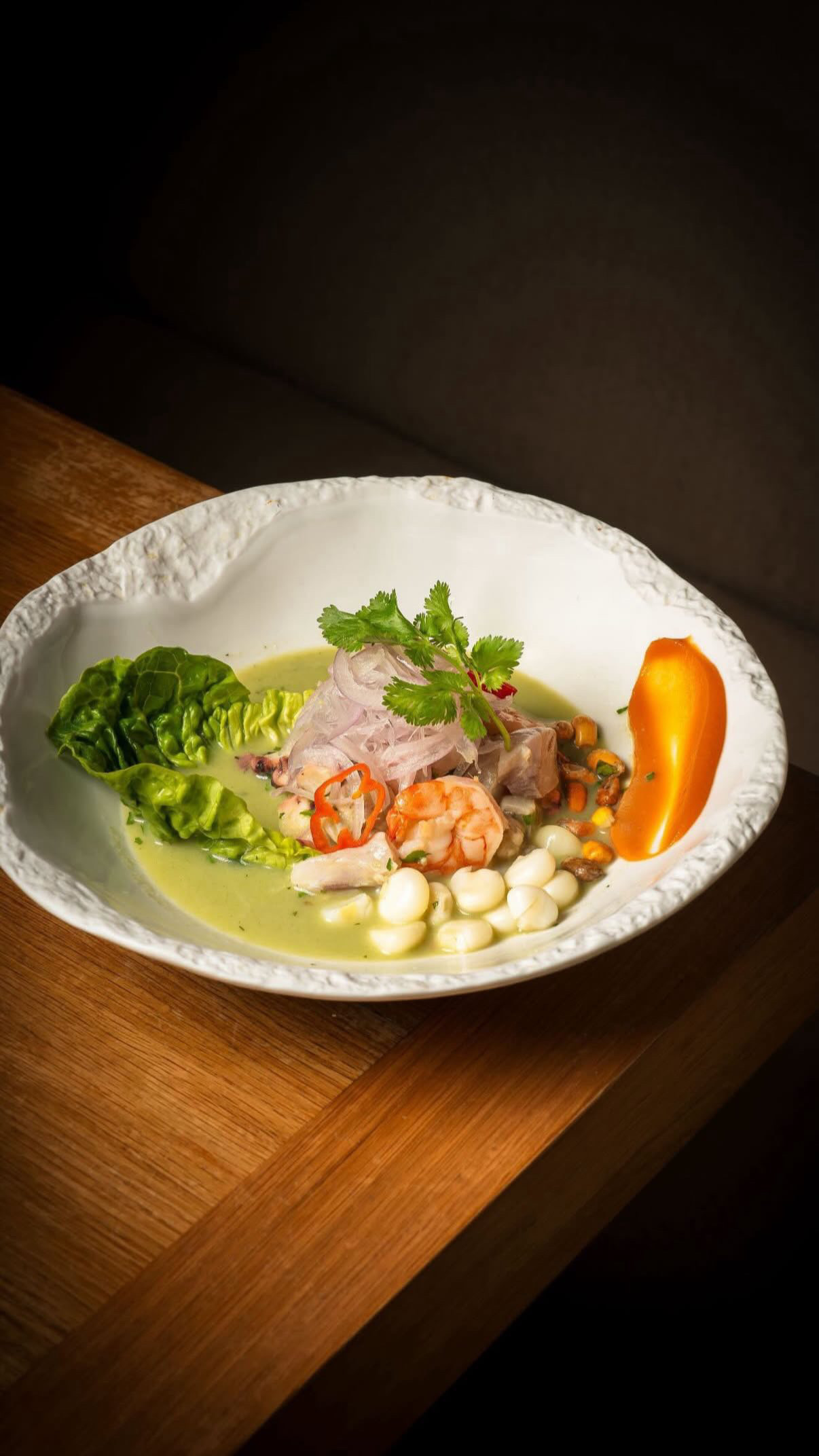 Ceviche con langostinos, camote y choclo en plato blanco