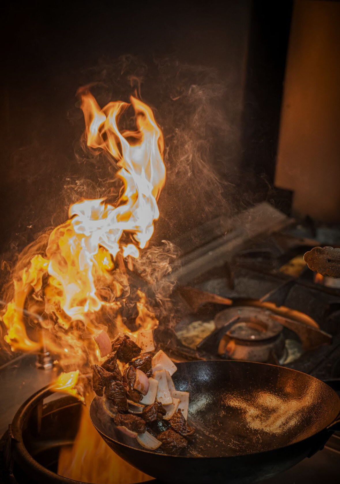 Llamas saliendo del wok en la cocina de Leche de Tigre